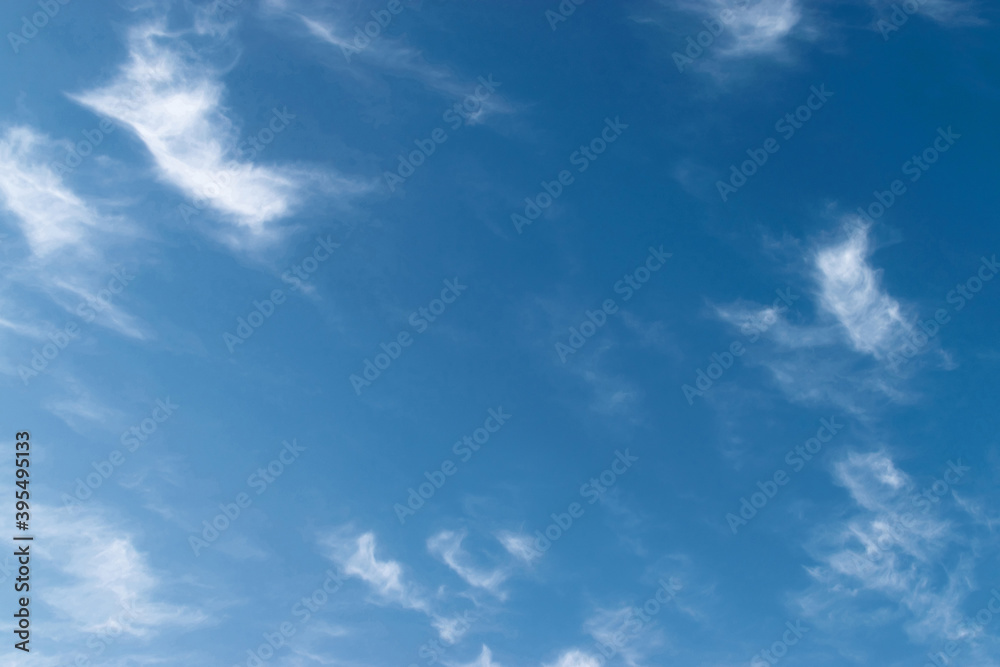 White feathery fluffy clouds on a blue sky, background and texture