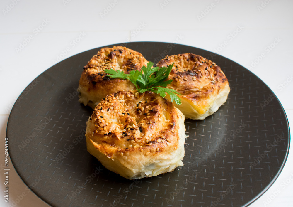 Delicious buns on a black plate on a white background