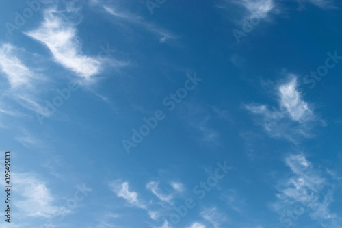 White feathery fluffy clouds on a blue sky, background and texture