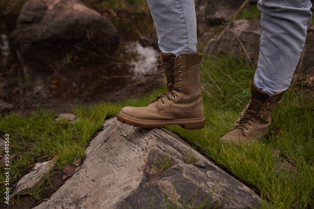 Woman wearing stylish hiking boots on rock, closeup Woman wearing stylish hiking boots on rock, closeup