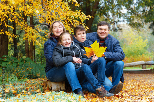 family relaxing outdoor in autumn city park, happy people together, parents and children, they talking and smiling, posing near yellow birch leaves, beautiful nature