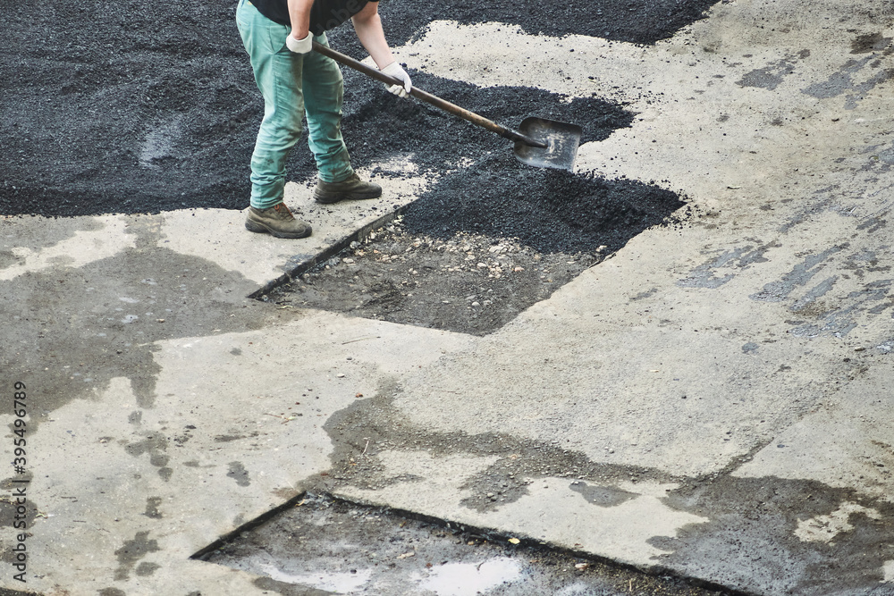 worker repairs asphalt. man throws the asphalt with shovel worker repairs asphalt. man throws the asphalt with shovel