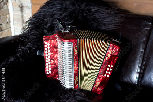 Hemsedal,Norway,08 september 2015-Traditional norwegian music instrument laying on coach with sheep wool on background,classic red accordion(bayan),scandinavian folk hobby photo