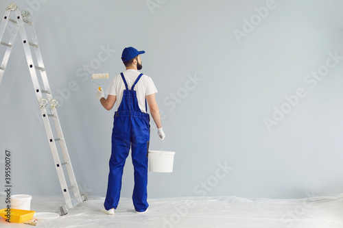 Bearded painter contractor preparing to paint wall photo