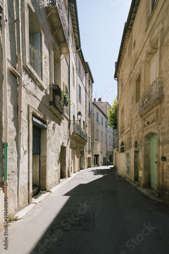 Fototapeta Naklejka Na Ścianę i Meble -  street view of narrow alley road lane in the sun and shadow leading the town city in summer in montpellier france old early building