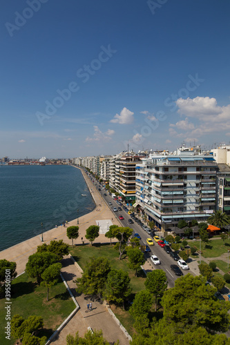 elevated view on thessaloniki during summer showing buildings by the sea, and a walking walk path by the water blue skies some clouds, port further down