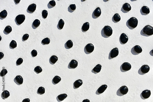 White wall with black stones background. Black and white texture.