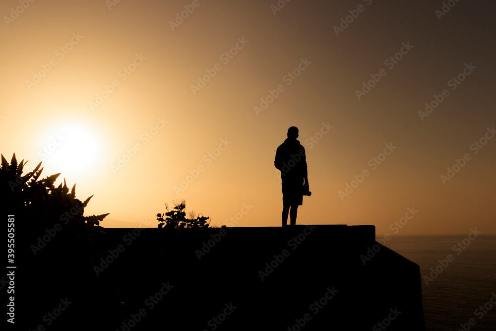 Silhouette of man with camera in hand at golden sunset in Tenerife. Silueta de hombre con cámara en la mano al atardecer dorado en Tenerife .