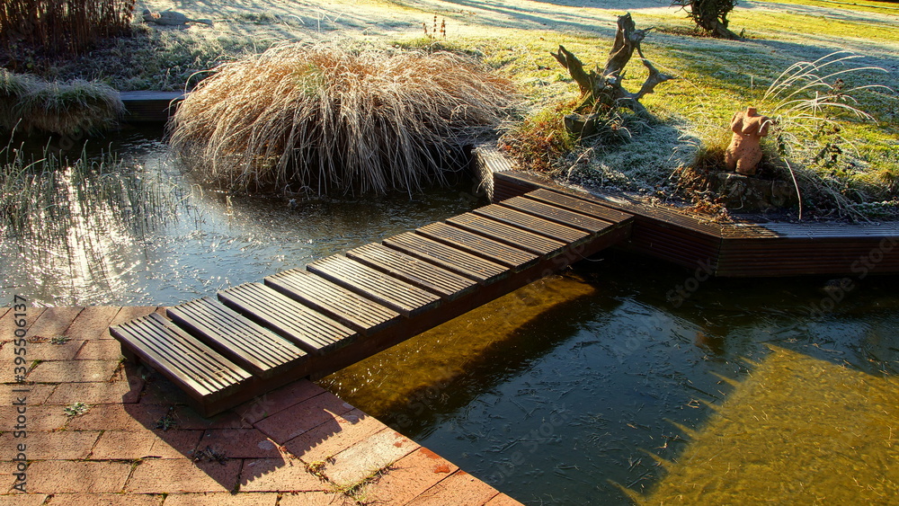 malerischer Gartenteich an frostigem mit Brücke und