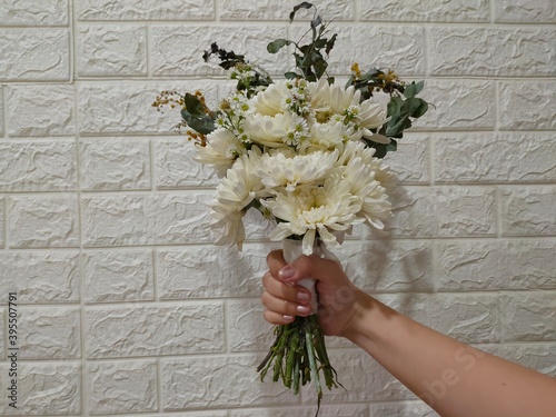 woman holding wedding bouquet with white brick background
