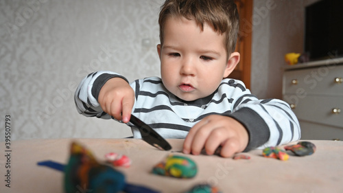 Little boy moulds from plasticine on table, Child hands playing with colorful clay, day care close up, tactility activity.