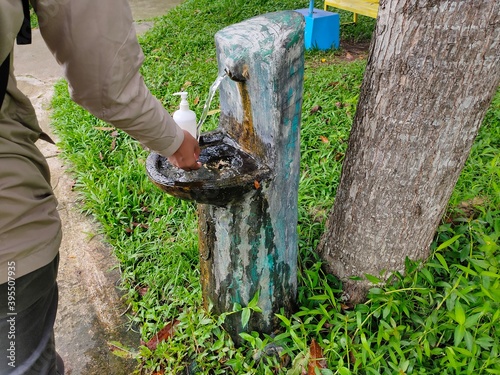 male washing hands in outdoor sink to prevent COVID-19