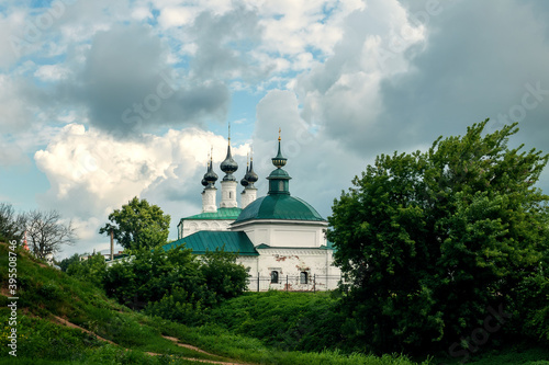 Ancient Church of the Entrance to Jerusalem and Pyatnitskaya Church, Suzdal. View from the hill in summer on a cloudy day photo