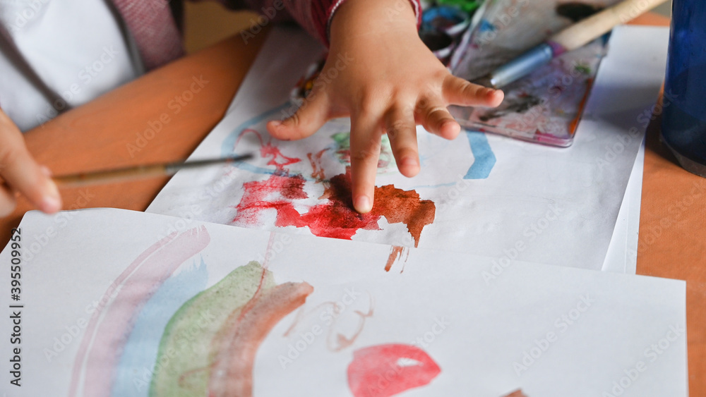 Little boy draws a rainbow on a sheet of paper in different colors. Home, game concept. Little boy draws a rainbow on a sheet of paper in different colors. Home, game concept.
