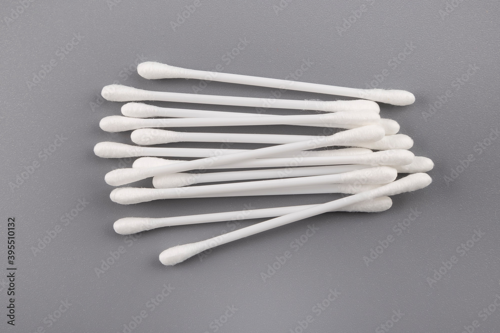 Cotton white swabs on gray background. Top view.Сoncept of using in cosmetic procedures,harm for ears. Cotton white swabs on gray background. Top view.Сoncept of using in cosmetic procedures,harm for ears.