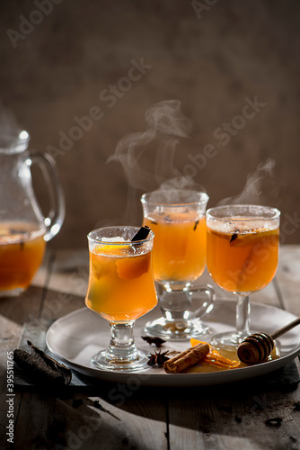 Hot mulled apple juice with spices, cinnamon, cloves, star anise, orange slices and zest