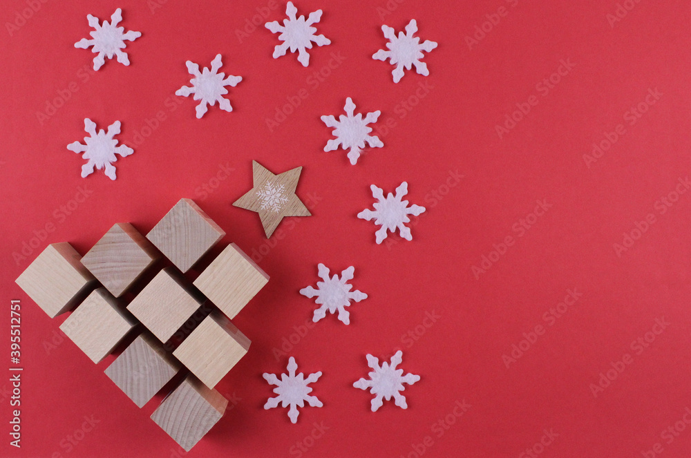 New Year tree made of wooden cubes with white snowflakes on a red background. Red background with wooden christmas tree with white snowflakes