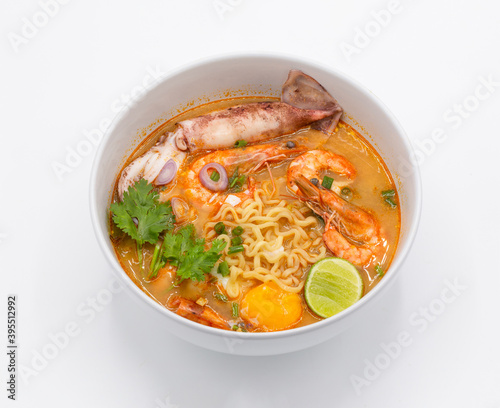 Tom Yum Kung is favorite taste of Thai cuisine with yellow noodle and vegetable ingredient in the white bowl. 