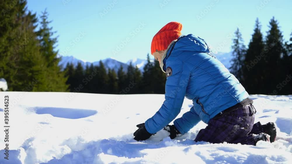 Young happy woman is rolling ball in frosty winter day, making snowman Young happy woman is rolling ball in frosty winter day, making snowman