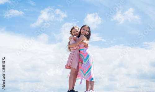 kid fashion style. female friendship or sisterhood. happy childhood. cute children on sky background. spring season weather. summer fashionable look. family love. beautiful teen girls sisters embrace