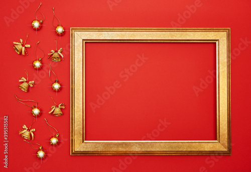 Christmas festive background. Gold balls, Christmas bells and a gold frame on a red background. View from above. Postcard for the New Year.