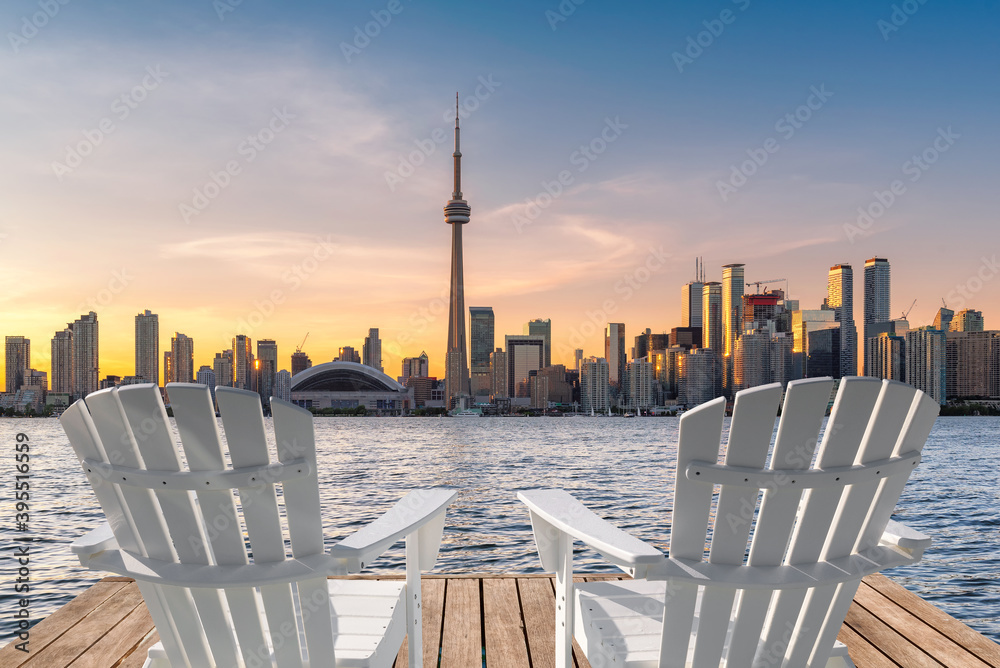 Fototapeta premium Toronto skyline in wooden pier with white chairs at sunset in Toronto, Ontario, Canada.