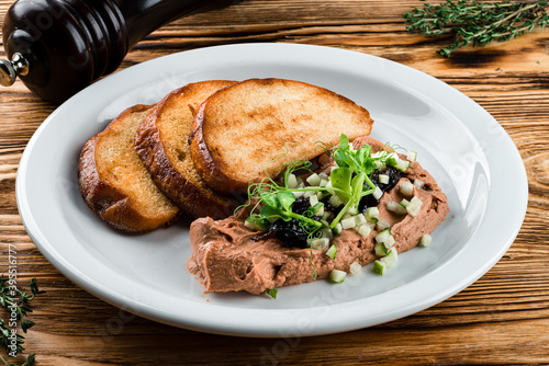Delicious chicken, duck, or rabbit liver pate or foie gras with spices. fried toast and pate with microgreens