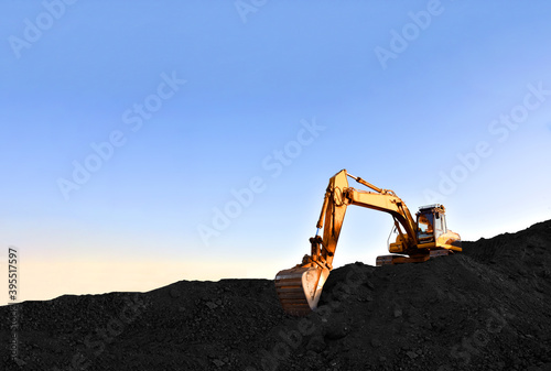 Excavator during earthmoving at coal open pit on sunset background. Construction machinery and earthworks heavy equipment for excavation at quarry. Recyclin and coal mining industry photo