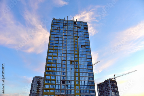 Mineral wool insulation of the facade building on construction site. Thermal protection of house. Installation double-glazed windows with frames. Tower cranes in action. Modern buildings background