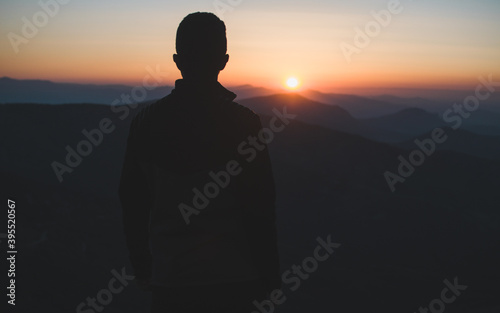 Hombre de espaldas a contraluz observando el amanecer en la Sierra de Guadarrama en Madrid photo