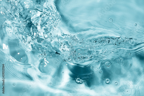 Splash of water flow with bubbles and ripples. Blue water texture. Selective focus. Motion blur