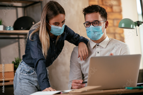 Businessman and businesswoman with medical mask in office. Colleagues working together. COVID - 19 virus protection.