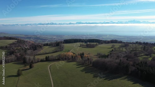 Stunning drone flight over lake Geneva and the Swiss alps. The haze and mist covers the mountains as the mountain range peaks immerge from the clouds and mist. photo