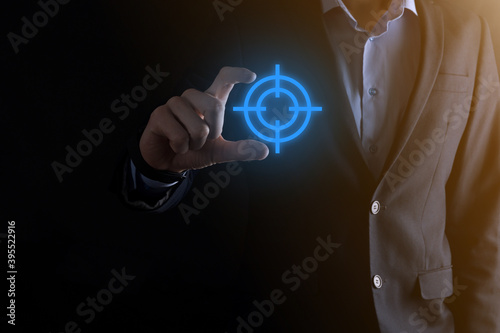 Targeting concept with businessman hand holding target icon dartboard sketch on chalkboard. Objective target and investment goal concept.