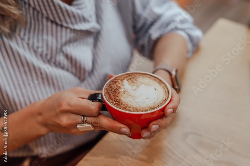 A red cup with coffee in the hands of a woman.
