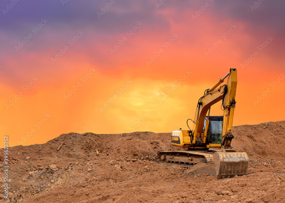 Excavator working on earthmoving at open pit mining on amazing sunset background. Backhoe digs sand and gravel in quarry. Heavy construction equipment during excavation at construction site Excavator working on earthmoving at open pit mining on amazing sunset background. Backhoe digs sand and gravel in quarry. Heavy construction equipment during excavation at construction site