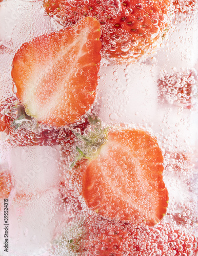 Closeup shot of a refreshing drink with a slice of strawberries and ice cubes photo