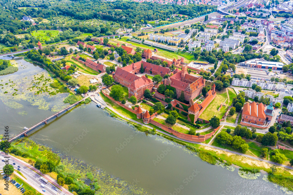 Medieval Malbork (Marienburg) Castle in Poland, main fortress of the Teutonic Knights at the Nogat river. Aerial skyline view of the city in fall in sunset light