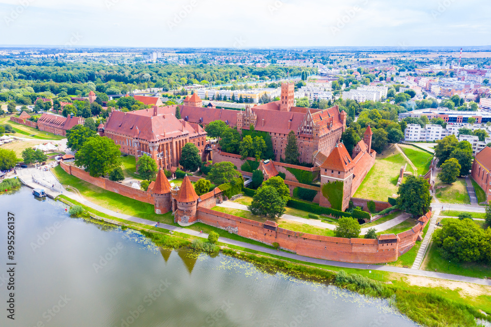 Medieval Malbork (Marienburg) Castle in Poland, main fortress of the Teutonic Knights at the Nogat river. Aerial view in fall in sunset light.