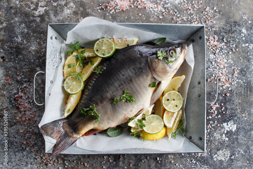 Fresh carp in a dish with lemon and lime