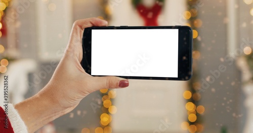 Close up shot of Caucasian female hand holding black smartphone with green screen while standing outdoors on New Year Eve. Cellphone with chroma key in woman hands on Christmas. Technology concept