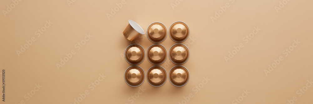 Caffeine, hot drinks and objects concept - close up of golden capsules or pods for coffee mashine on beige background. Top view with space for text. Flat lay.. Caffeine, hot drinks and objects concept - close up of golden capsules or pods for coffee mashine on beige background. Top view with space for text. Flat lay..
