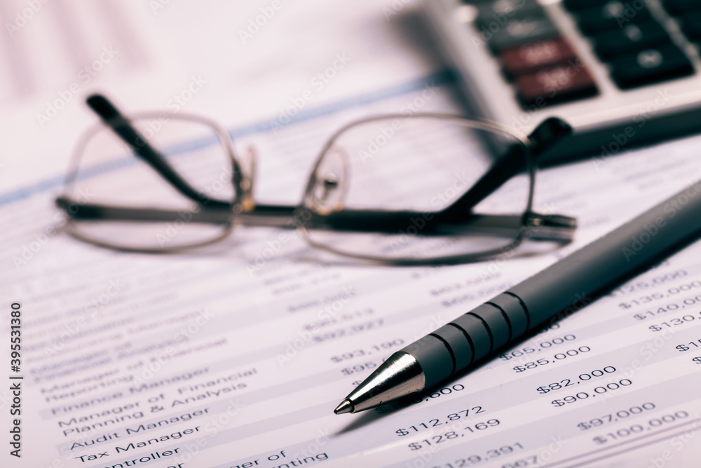 Pen, Eyeglasses and Calculator on Financial Figures Pen, Eyeglasses and Calculator on Financial Figures