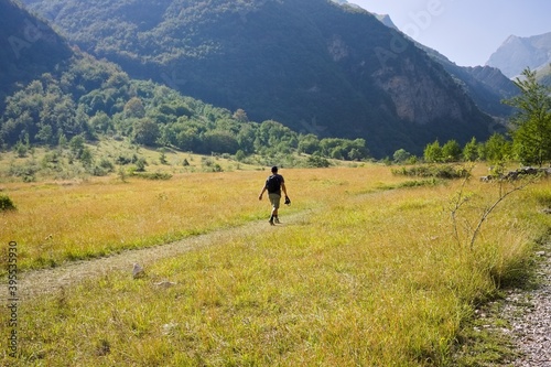 An isolated man is walking on an hike trail in a plain under the Sibillini Mountains (Marche, Italy, Europe)