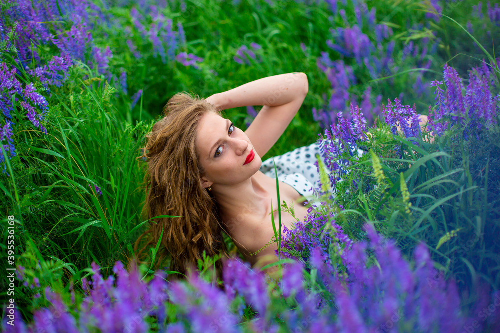 Beautiful young blonde girl in a green field among purple wildflowers. Wildlife beautiful girl Beautiful young blonde girl in a green field among purple wildflowers. Wildlife beautiful girl