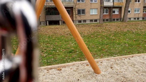 A cute baby boy in a red jacket and a blue hat on a chain swing at a park. 4K photo