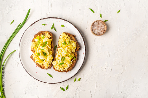 Scrambled Eggs on wholewheat toast. Delicious breakfast or snack on a light background, top view, copy space