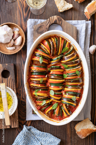 Ratatouille in a baking dish, bread, basil leaves, garlic, herb olive oil