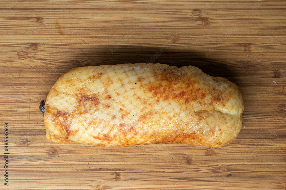 Whole smoked goose breast sat on wooden kitchen board top view skin side up Whole smoked goose breast sat on wooden kitchen board top view skin side up