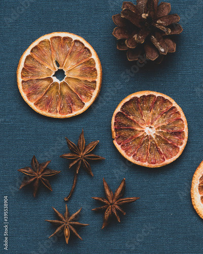 Pieces of dried oranges . And also a fir cone on a dark blue fabric background